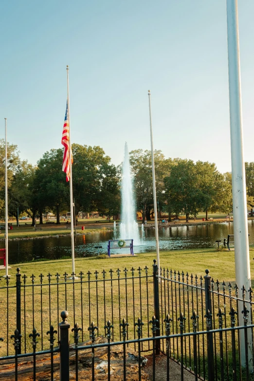 the water fountain with flags on each side is in a park