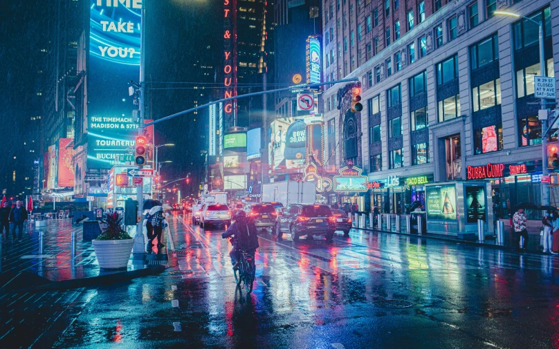 people are walking along a rainy street at night