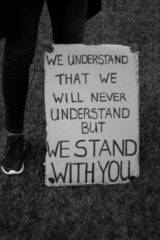 a protest sign with someones foot and the words we understand that we will never understand but we stand with you