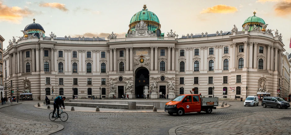 a bicycle rider passes in front of a large building