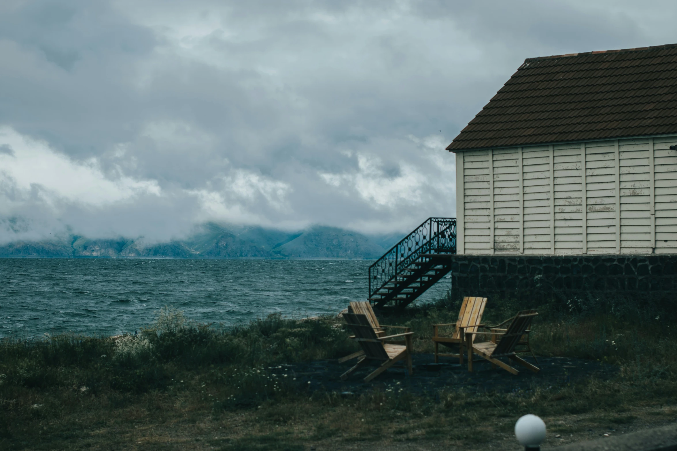 some chairs by a house on the side of the water