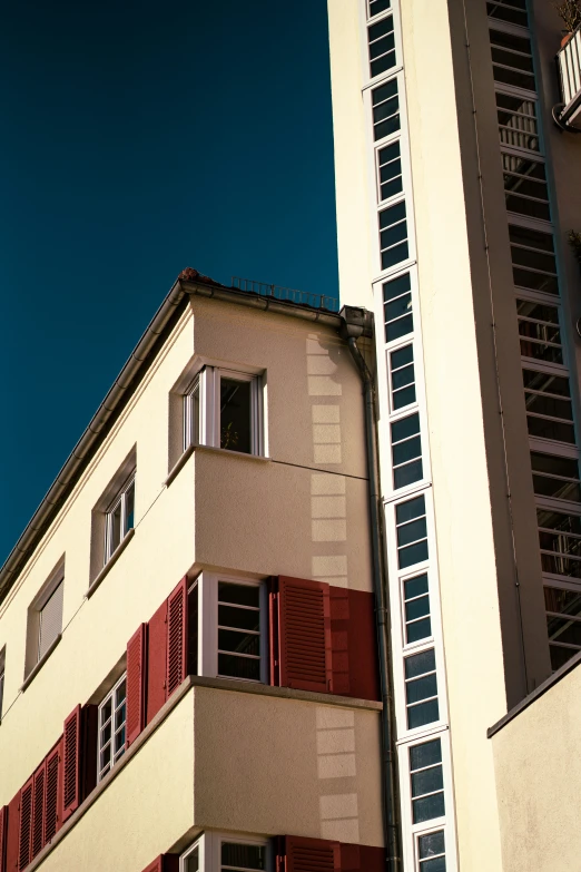 a tall building with windows and red shutters