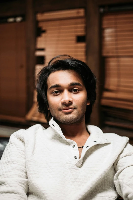 an indian man in white jacket sitting on chair with a book