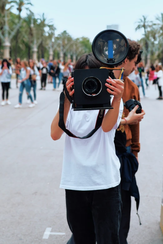 two young people taking pictures while a crowd stands in the background