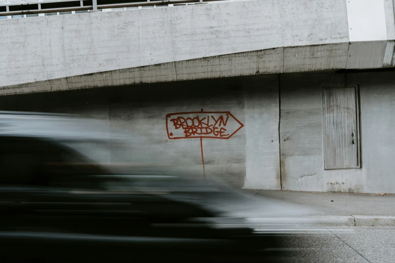 a car passing by with graffiti and a sign on the side