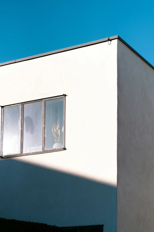 the sun is shining on a white building with open windows