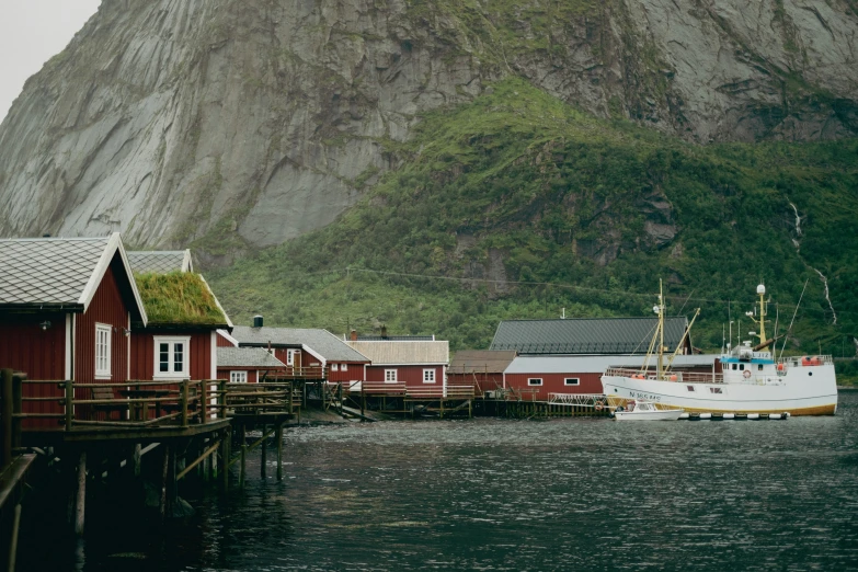 several small boats are parked on the water in front of mountains