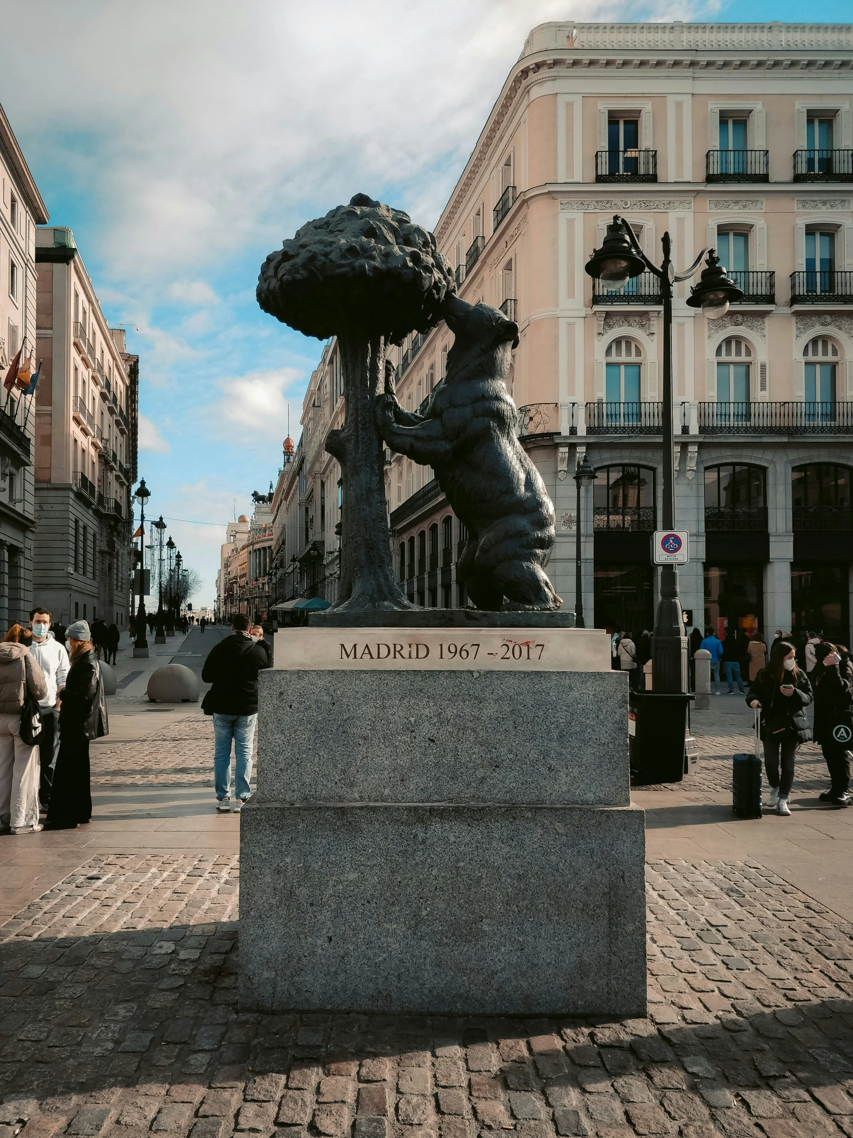 a public square with a statue in the middle and people walking around