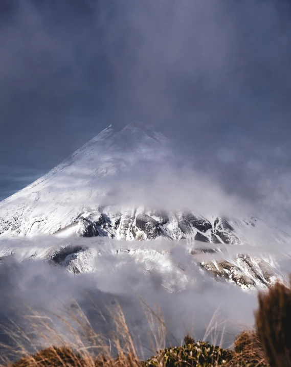 the snowy mountain range is covered with clouds