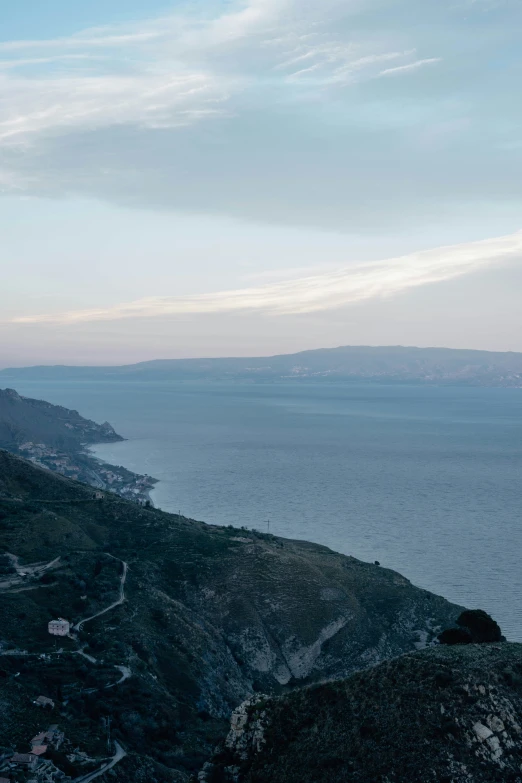 a person stands on the edge of a cliff by an ocean