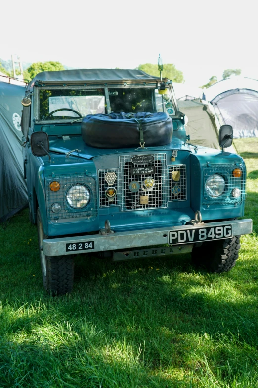 an old green jeep parked in a grassy field