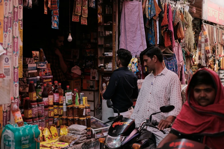 a man stands near a man on a scooter in a market