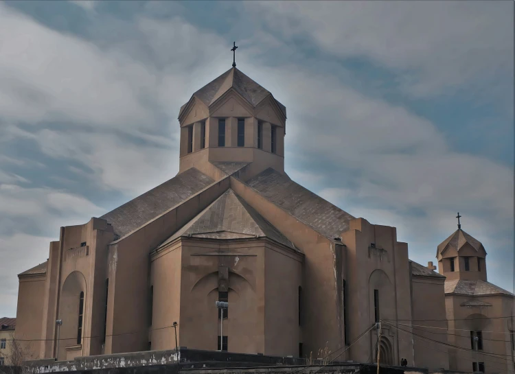 an old, brown church with towers under the cloudy sky