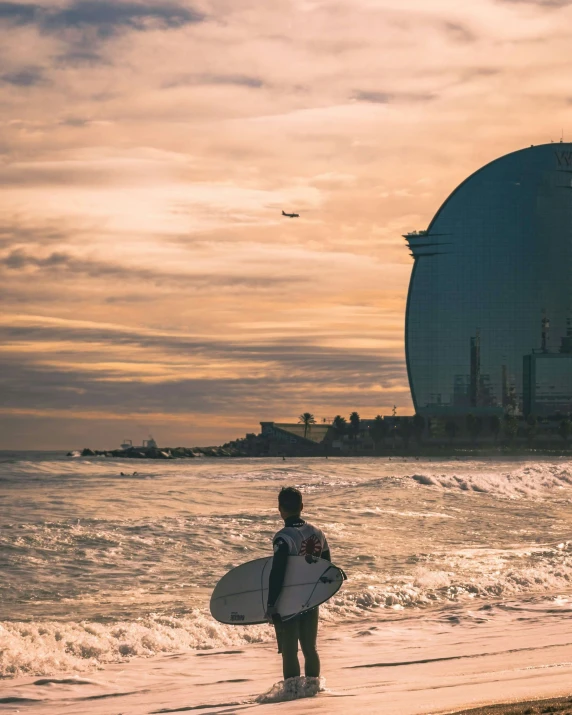 a surfer walking into the ocean carrying a surfboard