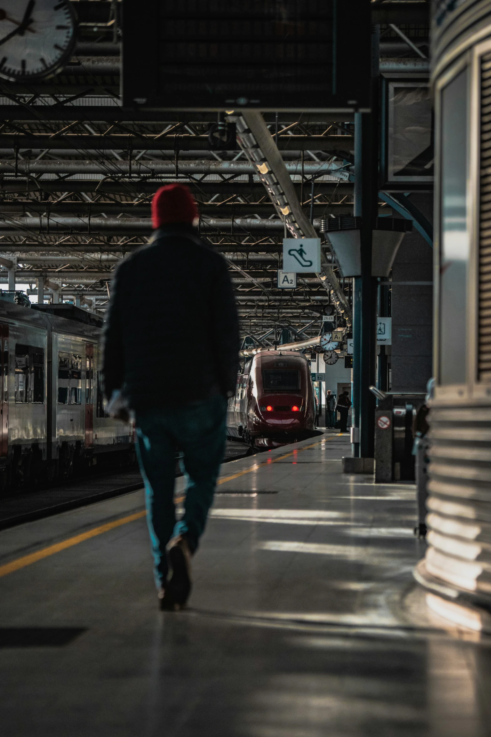 a lone person walking towards a train parked in a train station