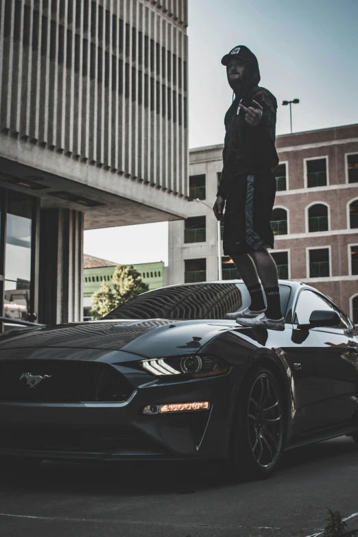 a man standing on the hood of a sports car