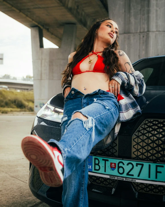 a beautiful woman in a red  top standing next to a car