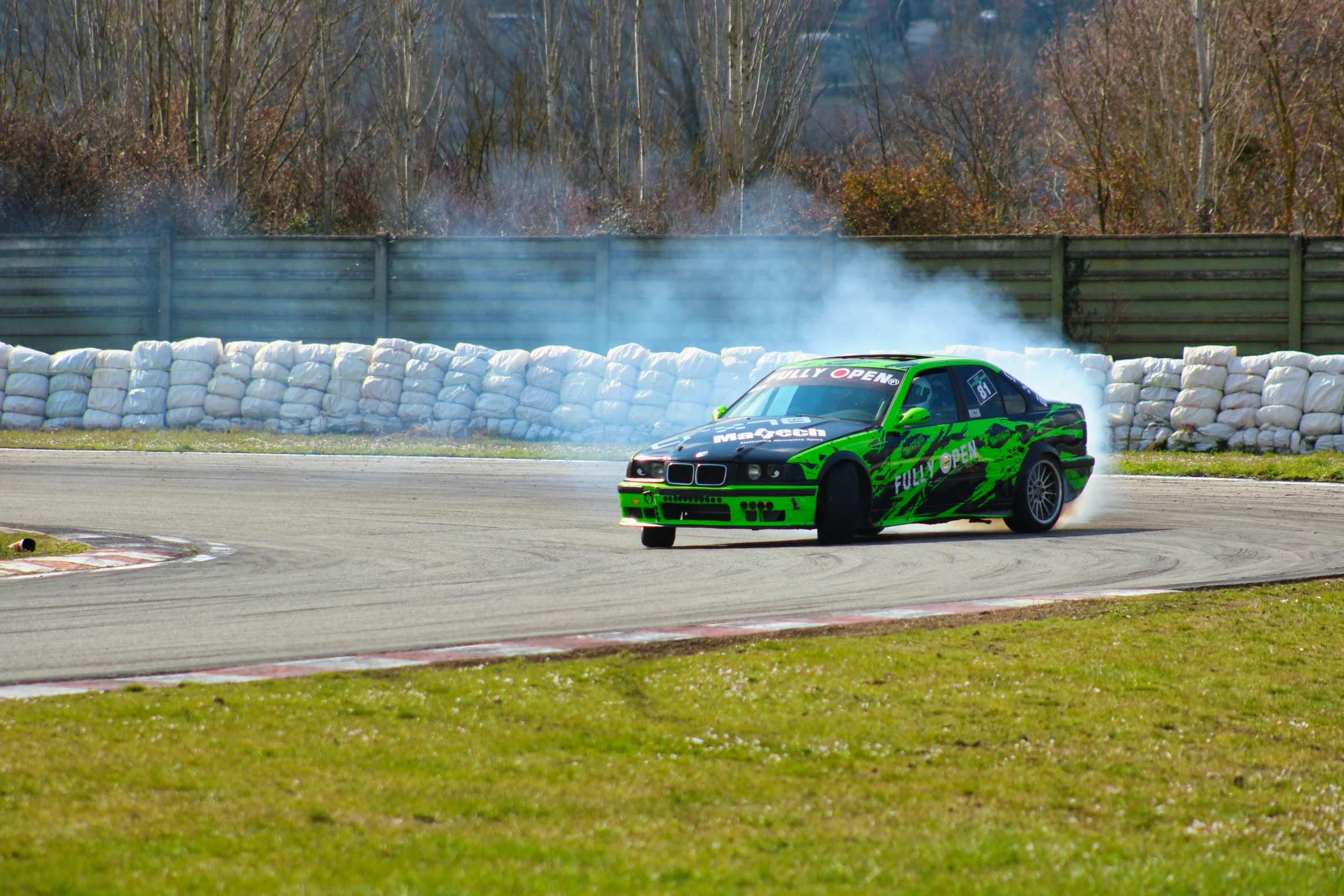 a green sport car driving around a track in front of a pile of rocks