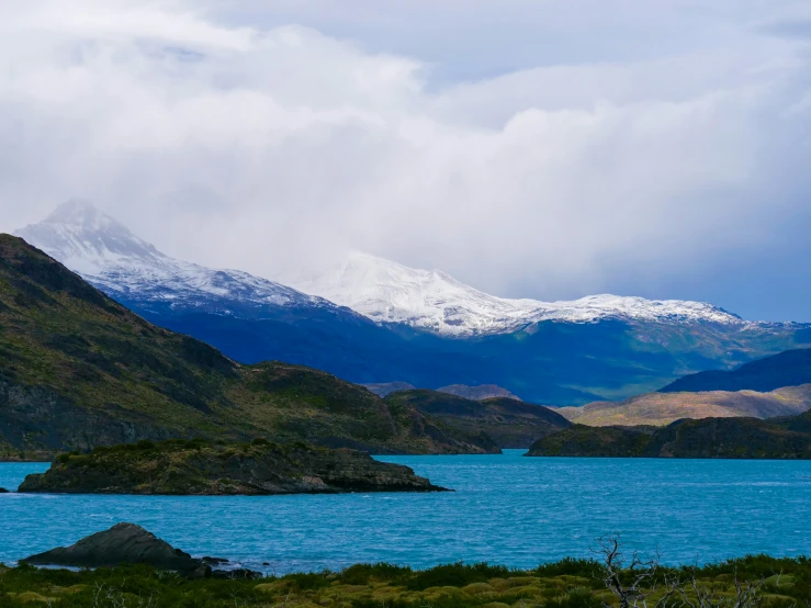 snow capped mountains stand over a lake in the foreground