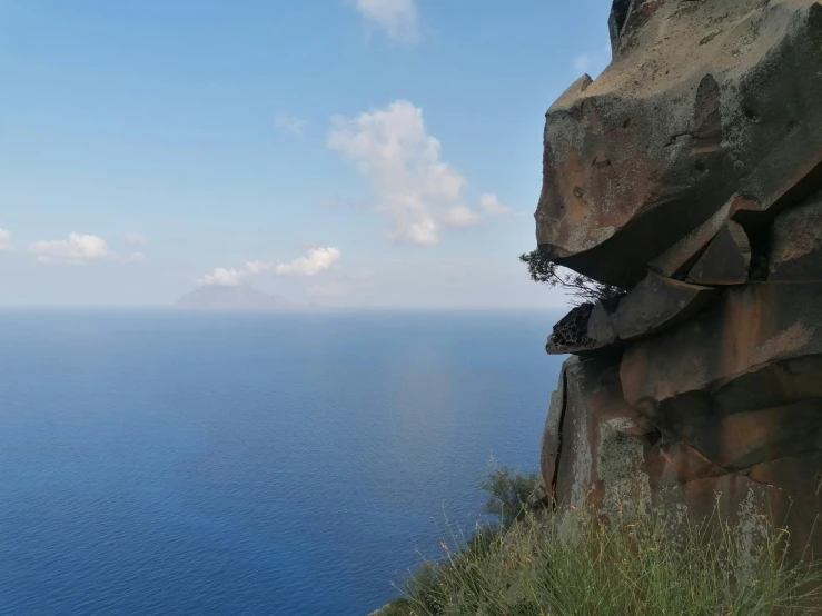 an extreme cliff next to the ocean on a sunny day