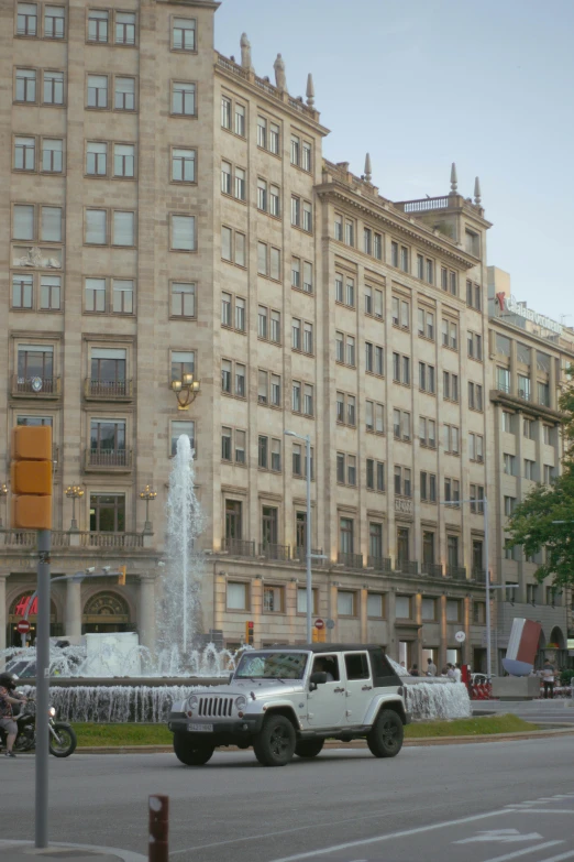 a large building sitting beside a fountain in a street