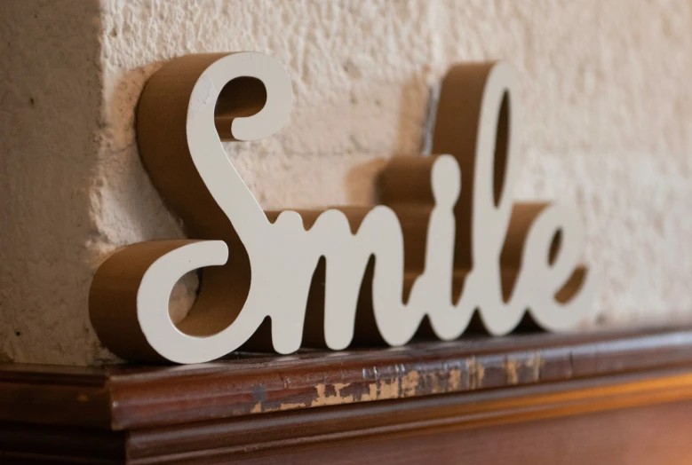 a wood sign that says smile sitting on a mantle