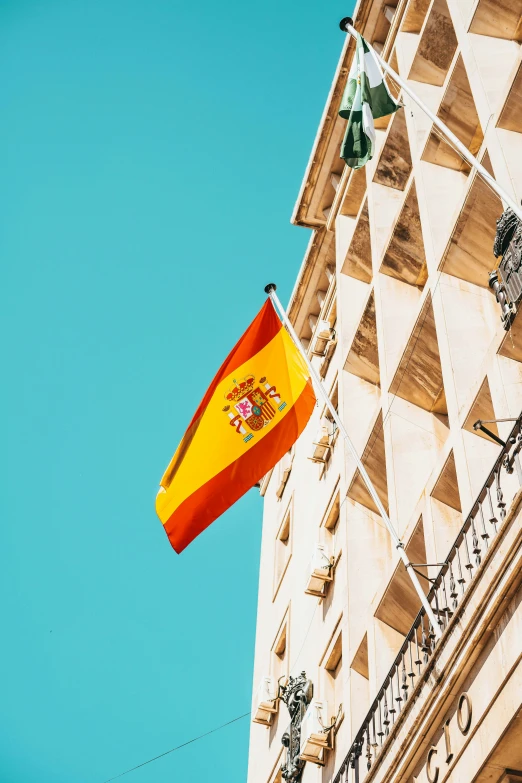 the spanish flag flies next to a white building