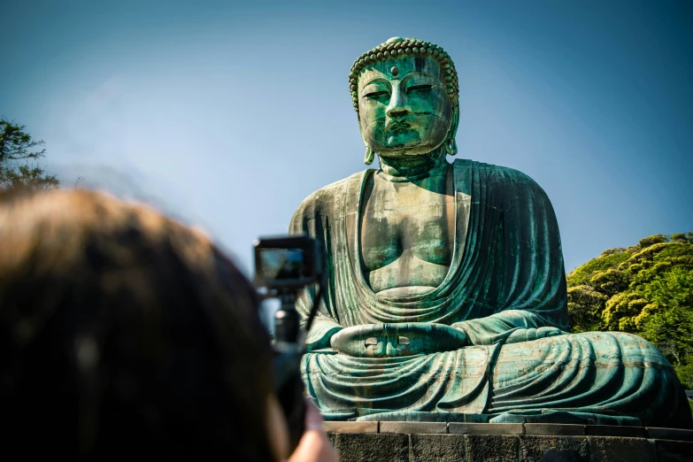 a person taking a pograph of a large buddha statue