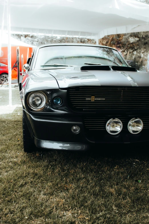 the front of a parked black car on top of a field