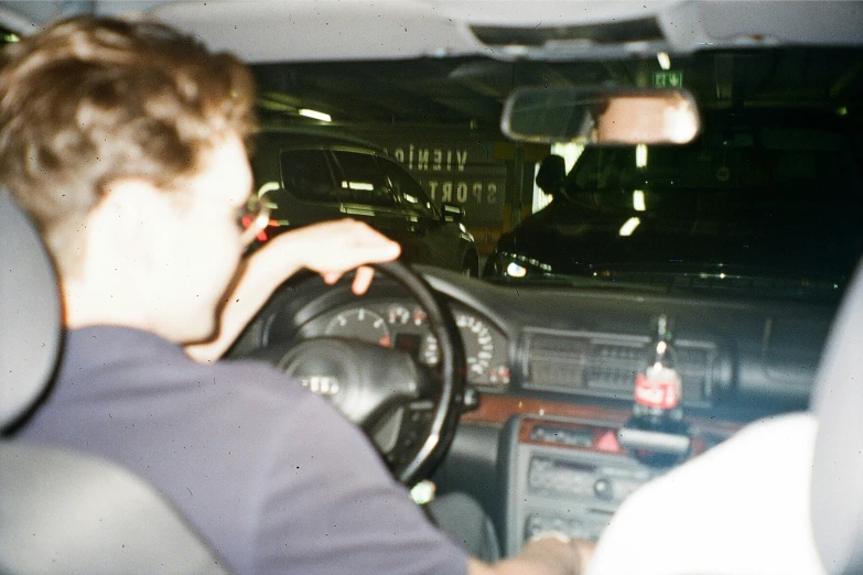 a man driving a car at night in a parking lot