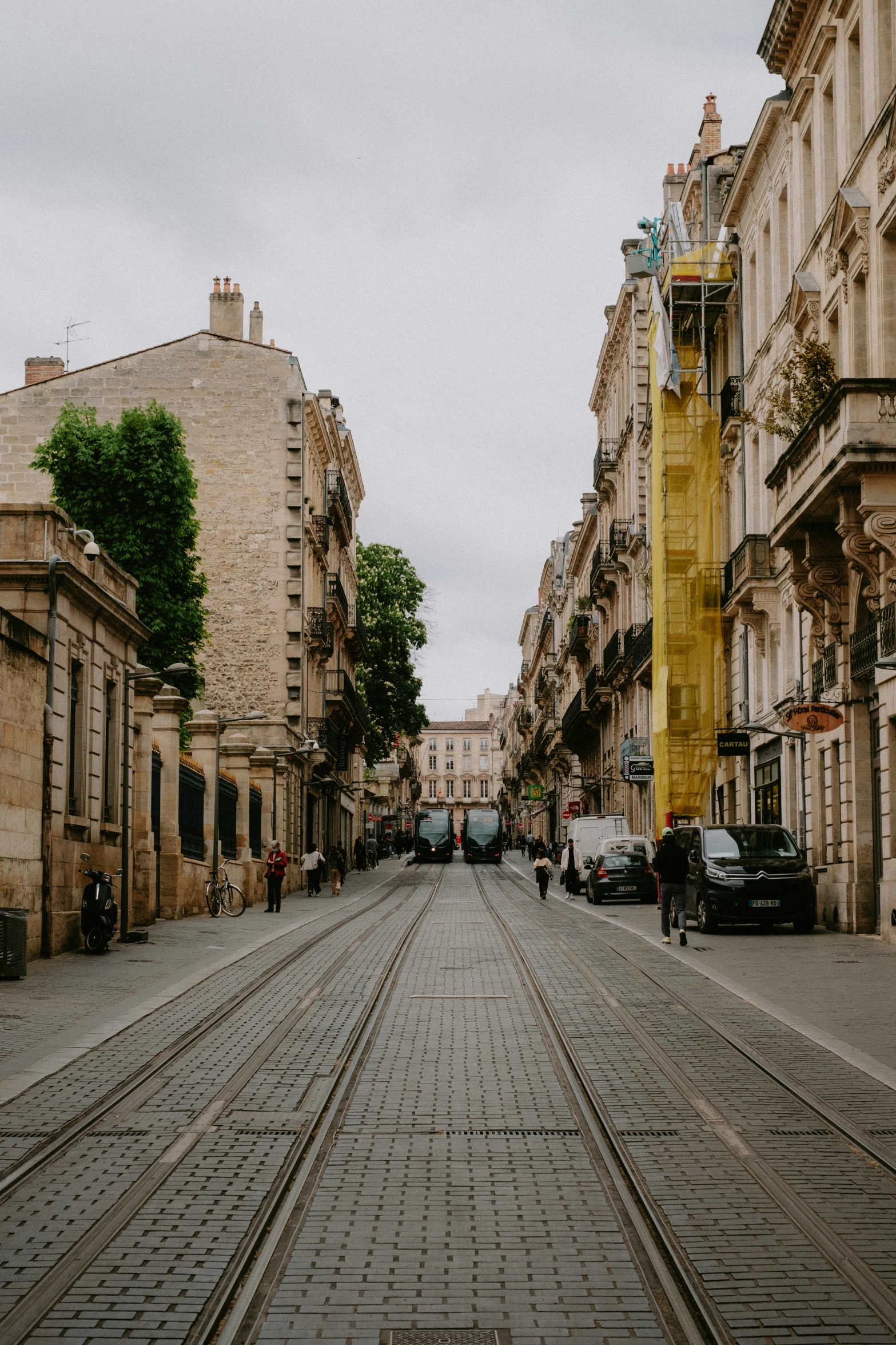 city street lined with buildings and cars, with empty track