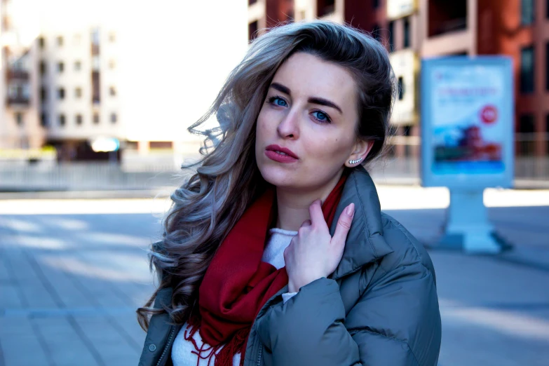 a woman in a parka and red scarf standing on a street