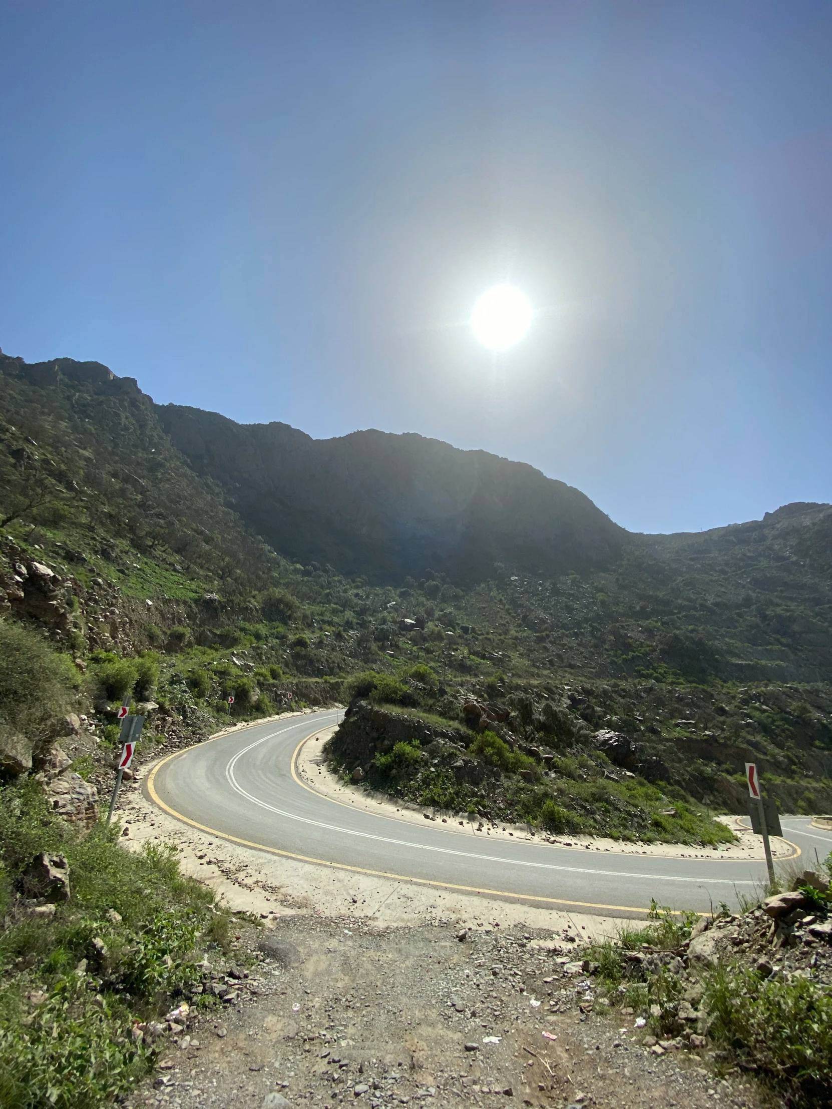 an empty road in a mountainous area with bright sun