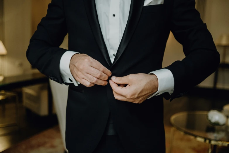 a person in a tuxedo tying his bow tie