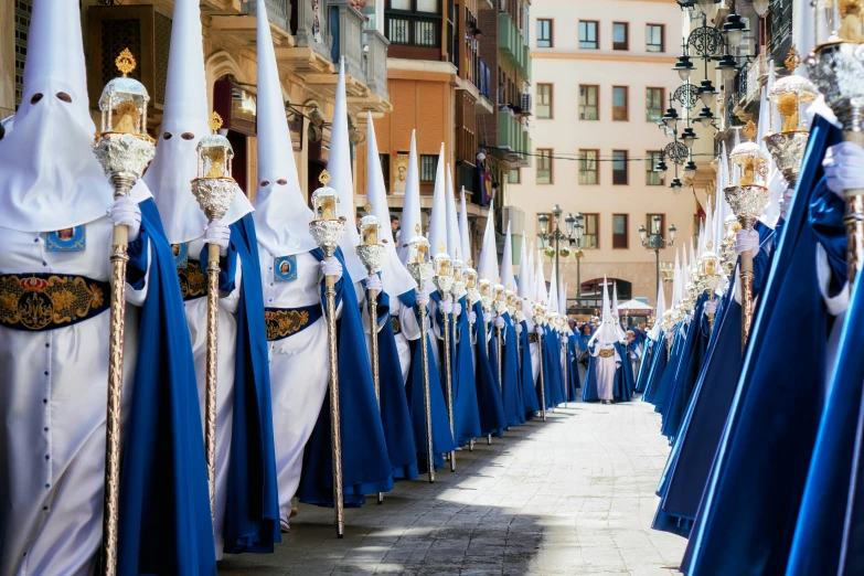 men dressed in blue robes in front of buildings