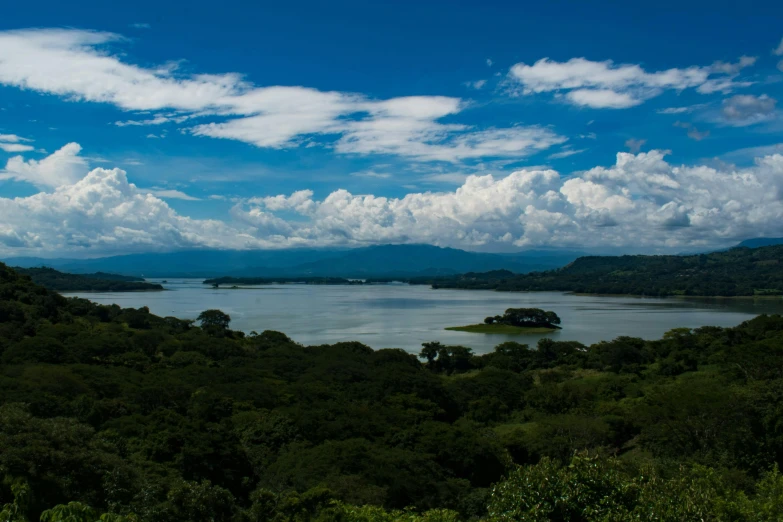 a blue cloudy sky is over a body of water with trees