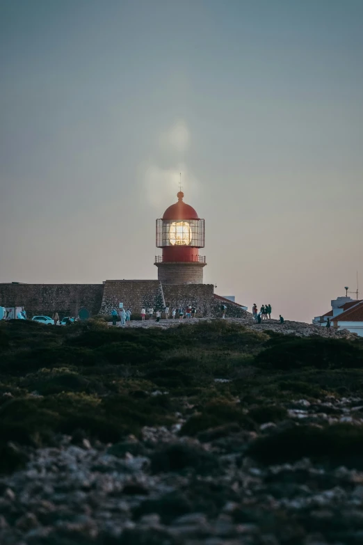 some people on rocks and a large lighthouse