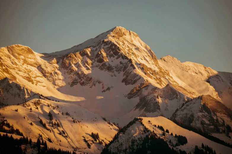 the top of the snow - covered mountains is just about as dawn