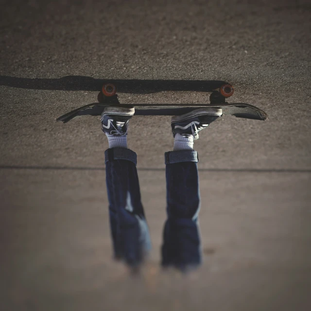 view down at one person's legs with a skateboard on the ground