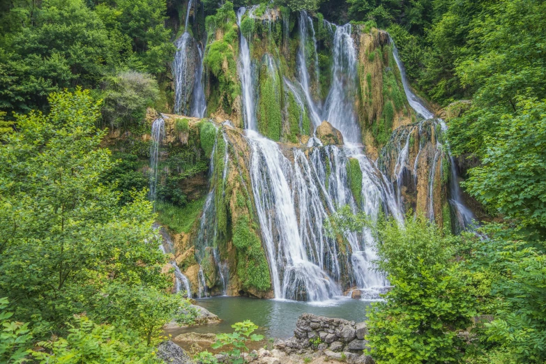 waterfall flowing through lush green trees in a park