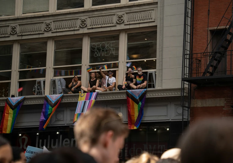 people are waving from a balcony where people are on top of windows