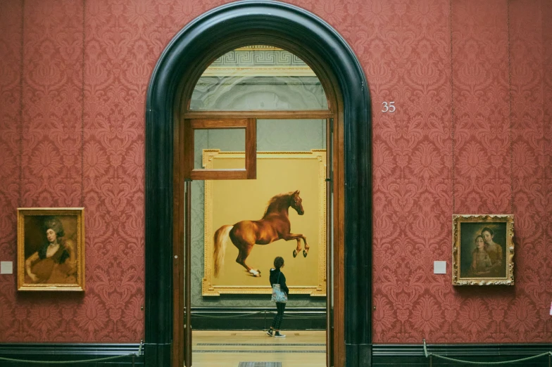 a man looking at paintings on the wall