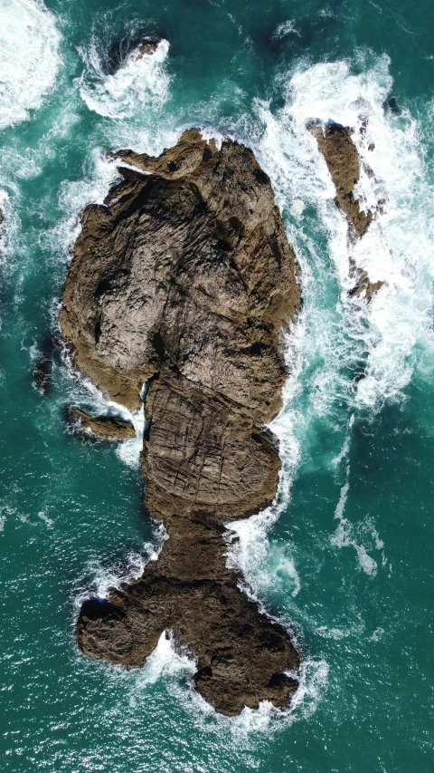 an image of the top view of a rock that is next to the water