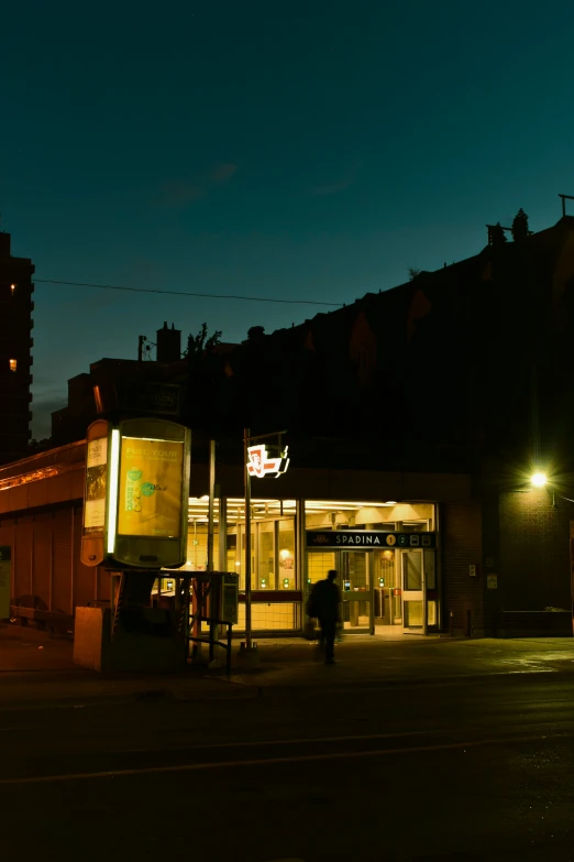 the person is walking in front of a store at night