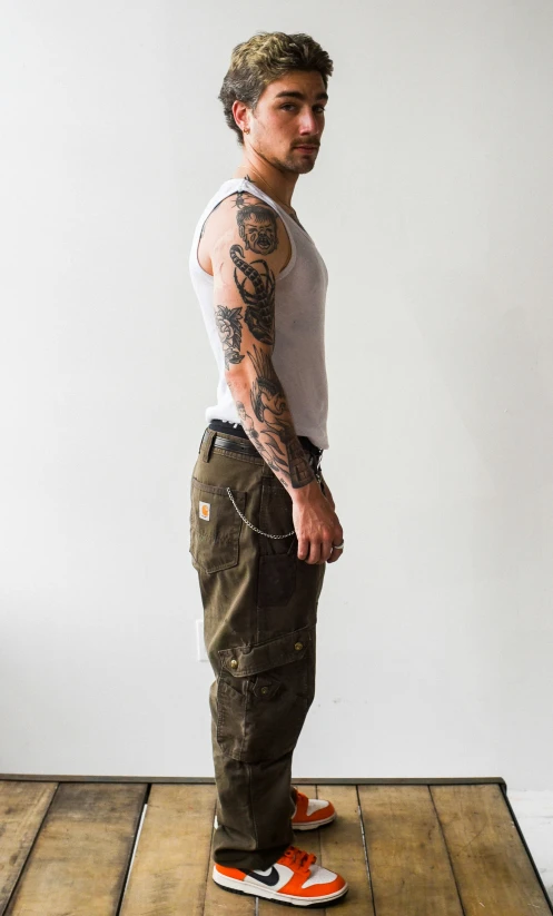 a man is standing on the wooden floor with a tattooed arm