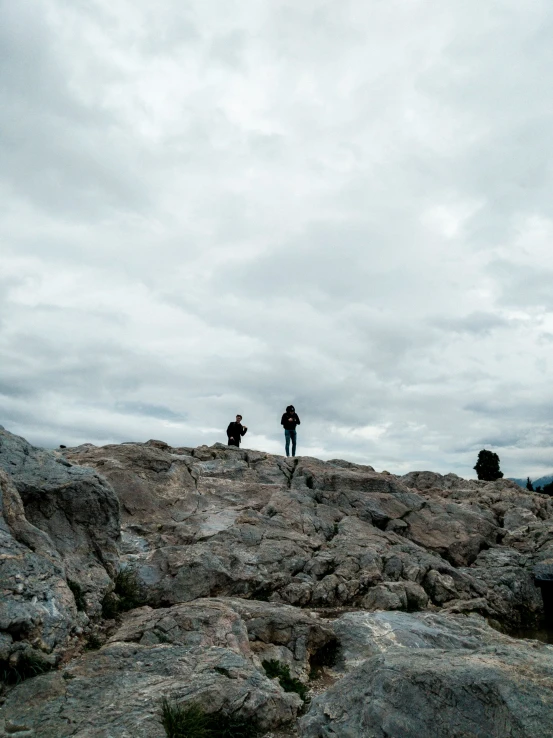 two people standing on top of a rocky hill