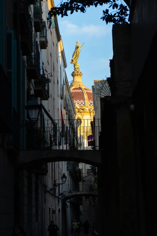 an old alley with buildings, people and a statue at the top