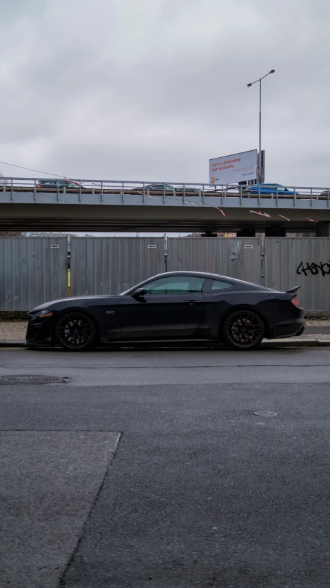 the black sports car is parked at a traffic light