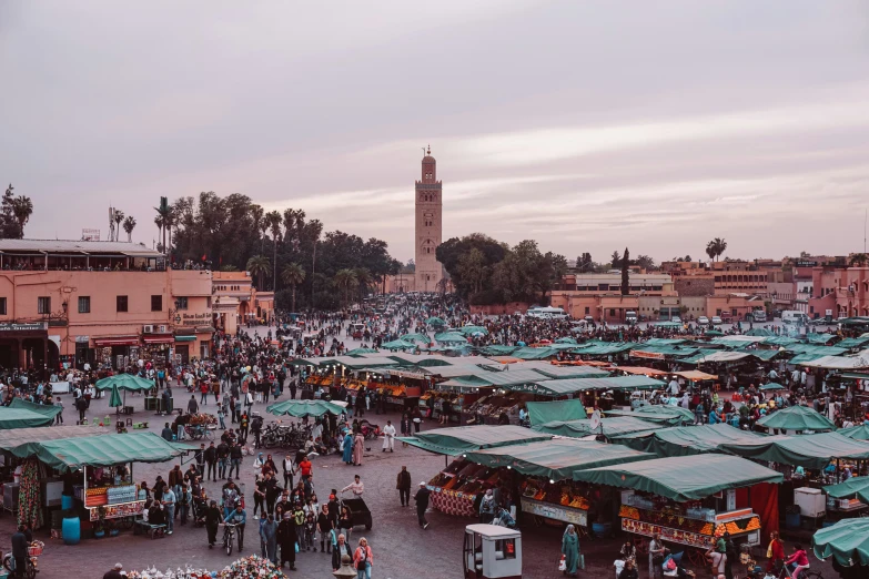 a busy outdoor marketplace in front of a tall clock tower