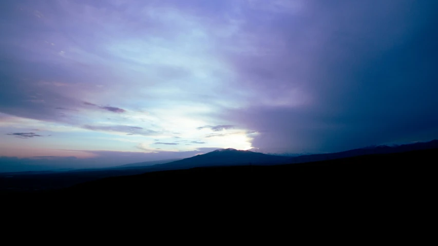 a very dark, stormy sky is shown over some mountains